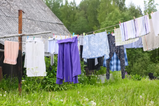 Different washed clothes hanging on a clothesline on rural yard.
Одежда сушится после стирки