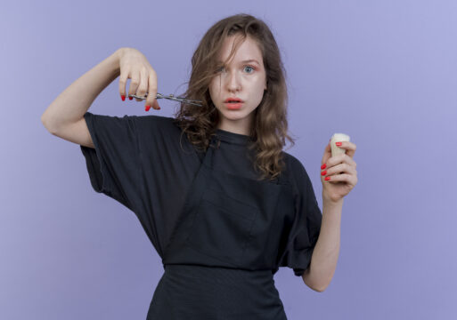 impressed young slavic female barber wearing uniform holding scissors and shaving brush isolated on purple background with copy space
Жвачка в волосах