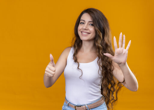 smiling young beautiful girl showing five and thumb up on isolated orange background with copy space
Цифра пять