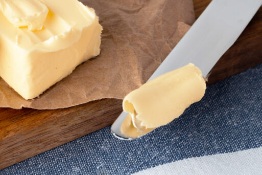 Wooden board with butter on blue checkered napkin. close up.
Сливочное масло